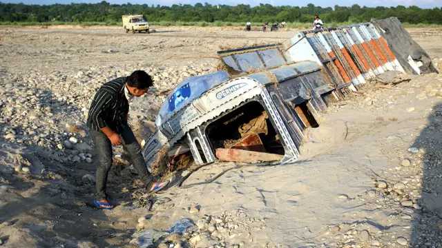 जम्मू के पास मलबे में दबे एक ट्रक को देखता एक व्यक्ति.