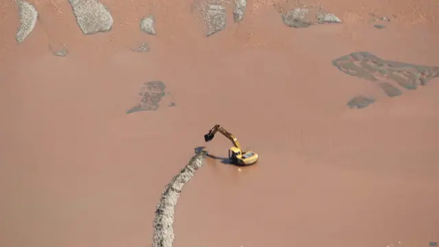 बाढ़ के बीच जम्मू के पास बांध बनाती एक जेसीबी मशीन