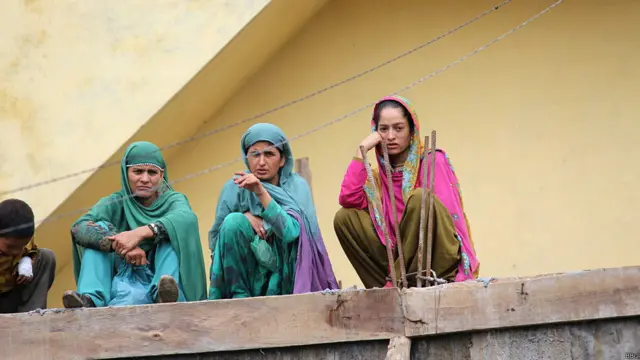 अपने घर की छत पर बैठकर बाढ़ की तबाही को देखते ग्रामीण.