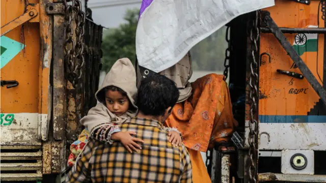 نوگام کے علاقے میں ایک خاندان امدادی ٹرکوں کے قریب پناہ لیتے ہوئے۔