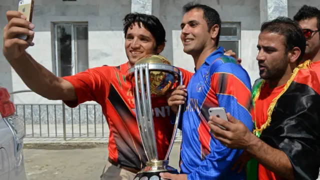 افغان لوبغاړو هم د کرېکېت اتلولۍ جام په ور رسېدو خوشاله کوله، ګلبدين نایب يې له محمد نبي سره خپلځانی انځور اخلي. 