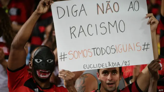 Torcedores exibem cartaz criticando o racismo no futebol