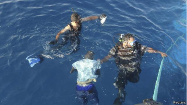 (أرشيف) عنصران من البحرية الليبية ينتشلان مهاجرا غرق الشهر الماضي قبالة السواحل الليبية. 