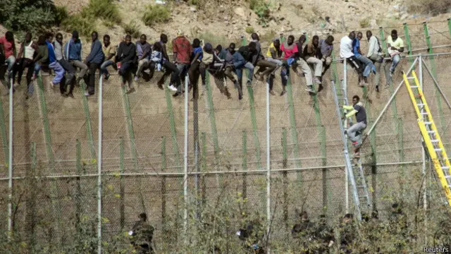 Migrantes encaramados en la valla