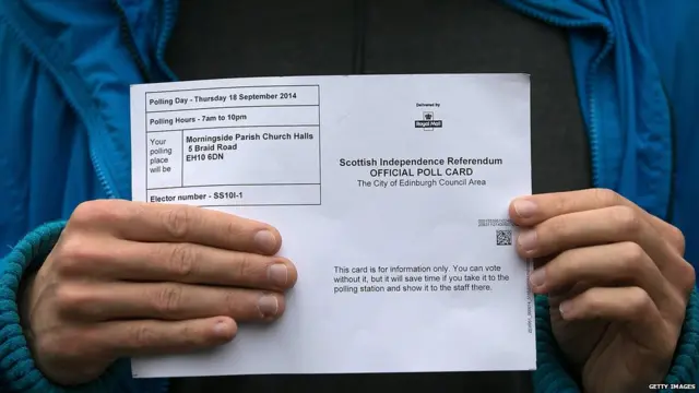 Um eleitor mostra sua cédula de votação para as câmeras antes de votar em Edimburgo.
