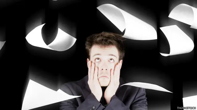 Empleado con papeles que caen sobre su cabeza