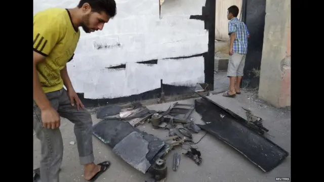 الرقہ میں دولتِ اسلامیہ کا کہنا ہے کہ فضائی حملوں میں شامل ایک ڈرون گر کر تباہ ہو گیا ہے۔ تصویر میں ایک شخص ڈرون کے ملبے کا جائزہ لے رہا ہے۔