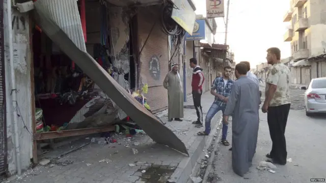 شدت پسندوں کا کہنا ہے کہ امریکی ڈرون الرقہ میں ایک مواصلاتی ٹاور سے ٹکرا کر تباہ ہوا۔ اس تصویر میں لوگ ایک تباہ شدہ دکان کا جائزہ لے رہے ہیں۔