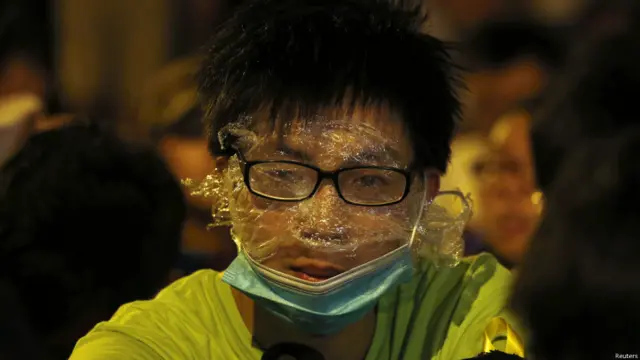 一名抗议学生用透明塑胶膜挡住脸，准备应对警察可能使用胡椒喷雾剂。