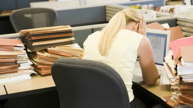 Empleada agobiada frente a su escritorio