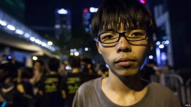 Kacamata, kaos, celana pendek, sepatu kets, adalah ciri khasnya