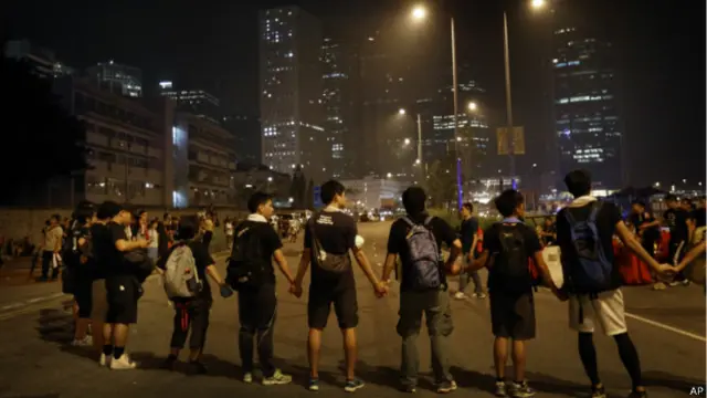 反对占路的示威者组成人链，阻止抗议民众进入道路。