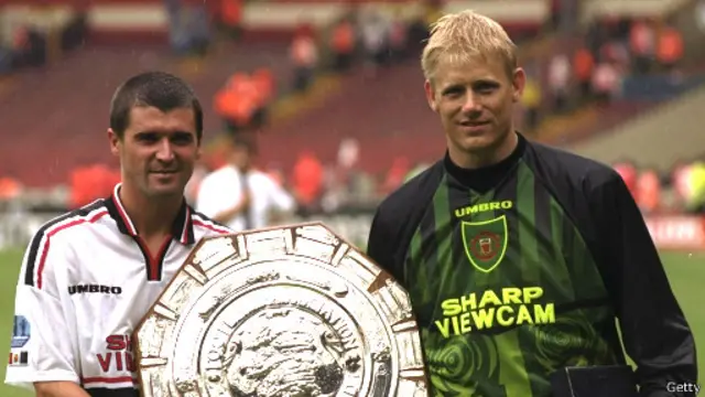 Roy Keane (kiri) dan Peter Schmeichel mempersembahkan berbagai trofi saat mereka membela Manchester United pada era 1990-an.