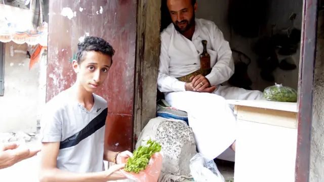 شاب يشتري القات في أحد أسواق صنعاء. والقات هو أحد النباتات المخدرة التي تشتهر بها اليمن. ويعد مضغ القات عادة إجتماعية أساسية في المجتمع اليمني وهي شائعة عند الذكور والاناث على حد سواء. وعادة ما "يخزن" اليمنيون أوراق نبات القات لساعات داخل الفم.