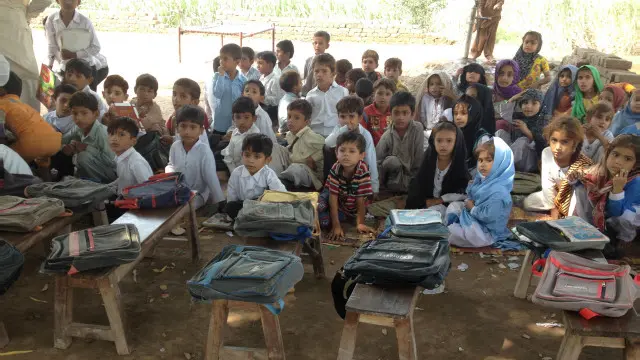 درخت کے نیچے سائے کی وجہ سے جوں جوں سورج اپنی جگہ بدلتا ہے بچے اپنے بنچ گھماتے رہتے ہیں تاکہ سائے تلے رہ سکیں