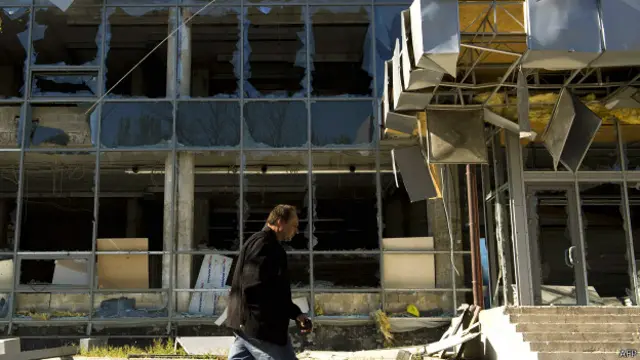 Мужчина идет мимо разрушенного здания в Киевском районе Донецка 7 октября 2014 года