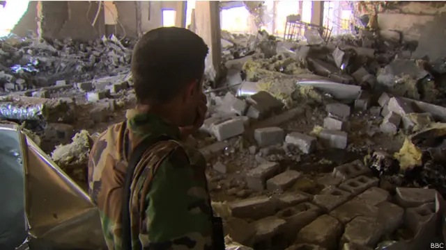 Un combatiente Kurdo mira a los restos del hospital en ruinas