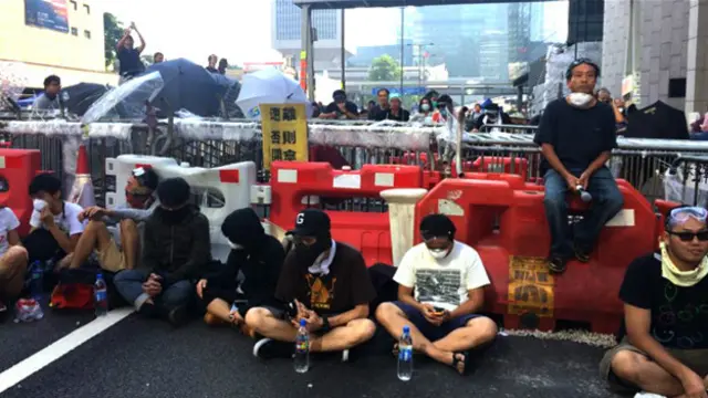 香港“占领中环”行动参与者在干诺道中中环段隔着剩余路障与警察对峙 （BBC中文网图片13/10/2014）