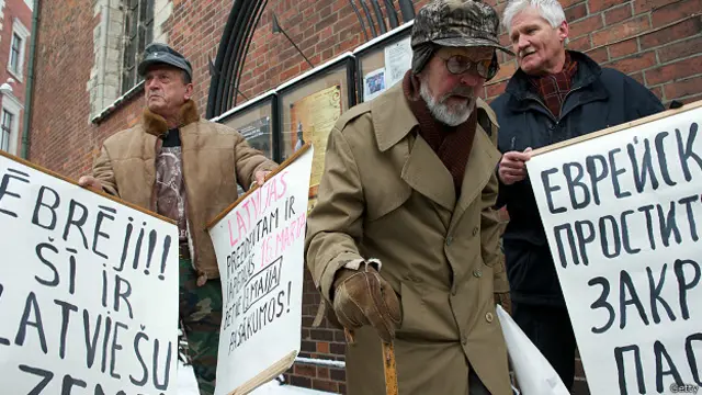 Ветеран Латышского легиона на фоне антисемитских плакатов