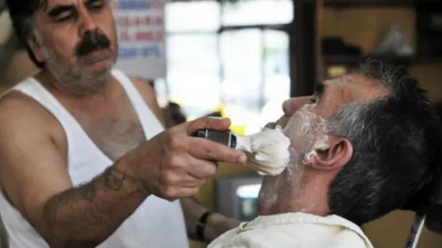 சவரக்கடையில் தாடியை மழித்துக் கொள்ளும் ஒருவர்