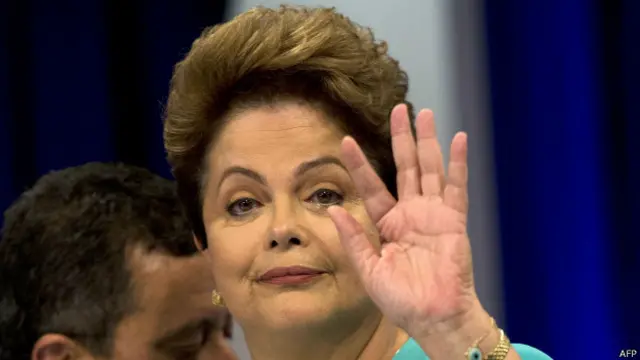 La presidenta y candidata brasileña Dilma Rousseff saluda con su mano.