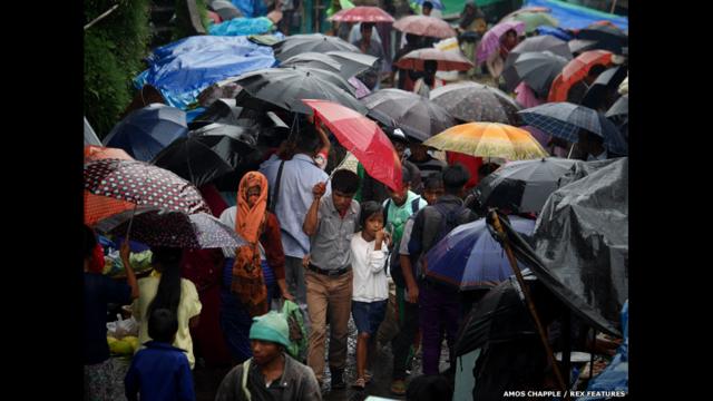 مجموعة من الناس تسير في ماوسينرام وهم يرتدون مظلاتهم الشهيرة.