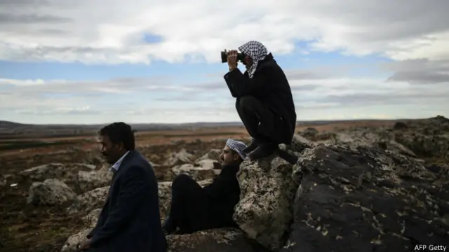 کرد باشندے کوبانی میں جاری جنگ کو دیکھتے ہوئے نظر آ رہے ہیں