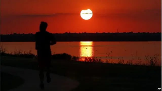Güneş tutulmasının sonlarına doğru göl kıyısında koşan adam