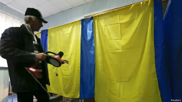 Член местной избирательной комиссии в Славянске несет лампу в кабинку для голосования