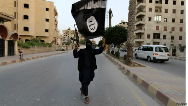 member loyal to the Islamic State in Iraq and the Levant (ISIL) waves an ISIL flag in Raqqa June 29, 2014