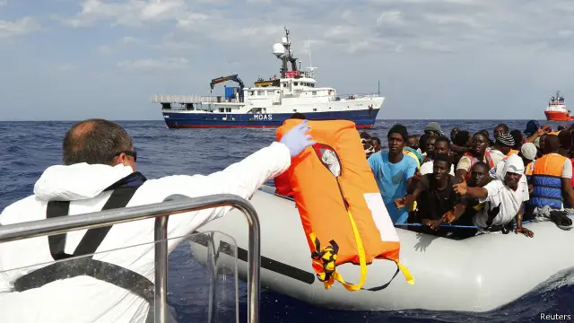 أحد عمال الإنقاذ يحاول إعطاء طوق نجاة لمهاجرين أفارقة قبالة الشواطيء الليبية.