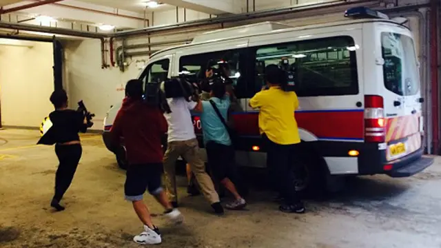 Kendaraan yang membawa tersangka pembunuh dua perempuan di Hong Kong dikerumuni wartawan.