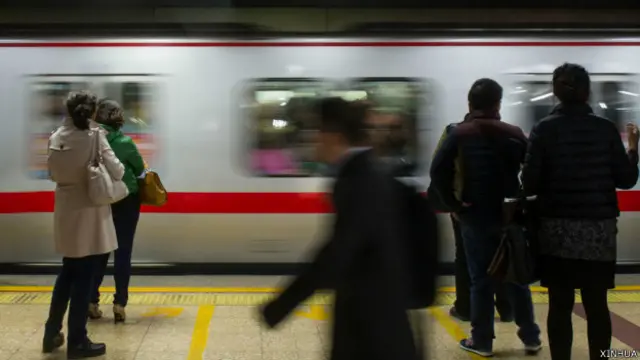 乘客在北京地铁国贸站站台上等候乘车(新华社图片3/11/2014)