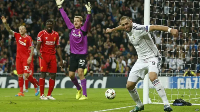 Karim Benzema merayakan golnya yang memenangkan Real Madrid, sementara para pemain Liverpool protes. 