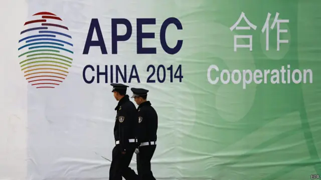 北京中国国家会议中心外两名警员在APEC会徽前走过（4/11/2014）