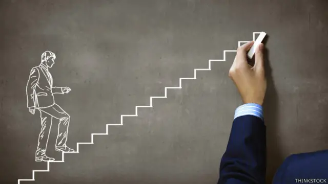 Una persona dibuja una escalera ascendente en una pizarra