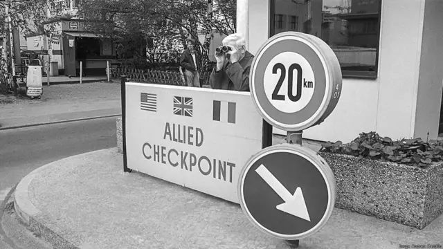 Hombre con binoculares en el Checkpoint Charlie, Berlin occidental