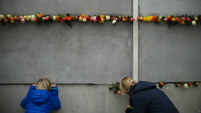 普通柏林人来到残留的柏林墙遗址前献花。