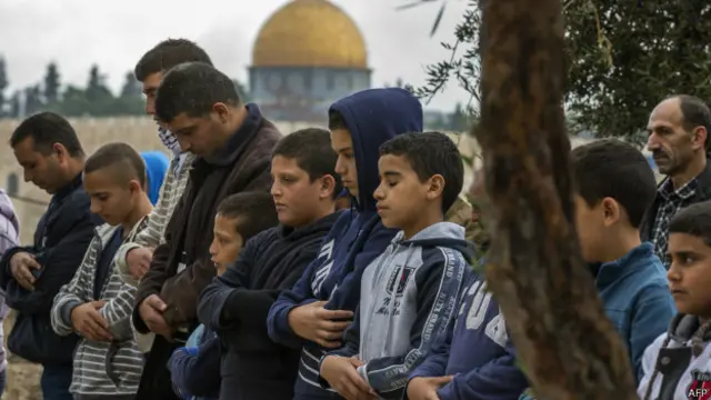 رجال يصلون وفي الخلفية مسجد قبة الصخرة