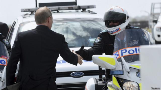 Владимир Путин пожимает руку местному полицейскому накануне отлета с саммита G20 в Брисбене 16 ноября 2014 г.