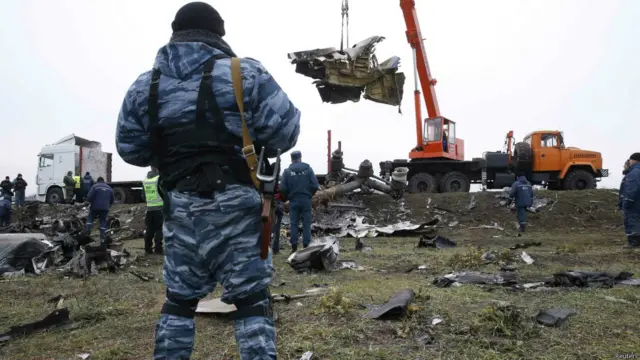 A pro-Russian separatist watches as a crane carries wreckage of the downed Malaysia Airlines flight MH17 at the site of the plane crash near the village of Hrabove (Grabovo) in Donetsk region, eastern Ukraine November 16, 2014.荷兰清理人员在坠机现场清理残骸。