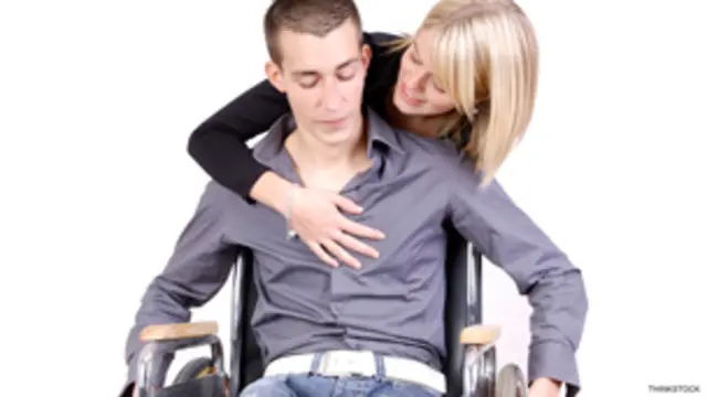 Mujer junto a un hombre en silla de ruedas.