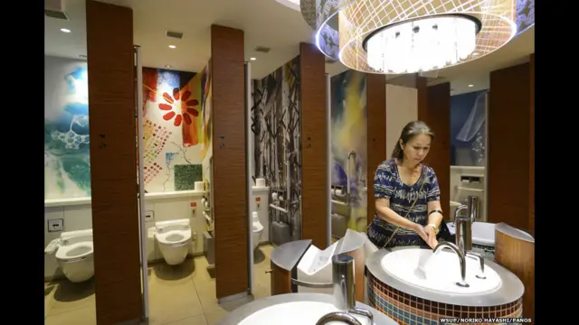 ဂျပန်နိုင်ငံ တိုကျိုမြို့မှာ နေတဲ့ ၆၁ နှစ် အရွယ် Eiko တစ်ယောက် သူ့အိမ် အနီးမှာ ရှိတဲ့ စျေးရုံကြီးရဲ့ အများသုံး အိမ်သာကို သုံးနေစဉ်။ သူ ကလေးဘဝ တုန်းကတော့ အများသုံး အိမ်သာတွေဟာ နံစော် ညစ်ပတ် နေခဲ့ပေမယ့် အဲဒီ အချိန်ကတည်းက ဒီ အိမ်သာတွေကို သုံးရတာ သက်သောင့် သက်သာ ရှိခဲ့တယ်လို့ ပြောပါတယ်။ အခုတော့ အဲဒီ အများသုံး အိမ်သာမှာ တစ်ပတ်လည် အသံစနစ်တွေ၊ အပူပေးထားတဲ့ ခုံတွေ ထားရှိလာတဲ့ အပြင် အိမ်သာတွေနဲ့ ကပ်ရပ်မှာလည်း တီဗီကြည့်တာ၊ ခြေထောက် အနှိပ်ခံတာတွေ လုပ်နိုင်ပါသေးတယ်။