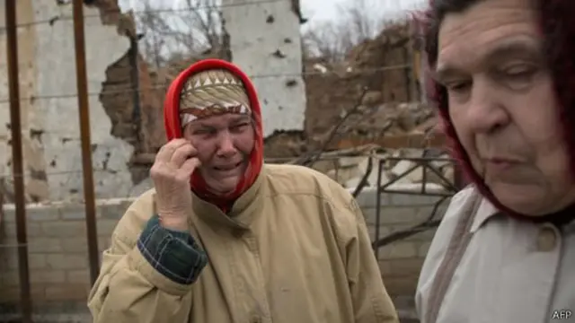 این زن در کنار خانه‌اش که در اثر جنگ در دونتسک ویران شده است گریه می‌کند