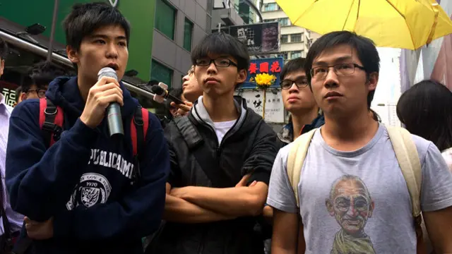 学联副秘书长岑敖晖（左）与学民思潮召集人黄之锋（中）等在旺角弥敦道口向执达主任喊话（BBC中文网图片26/11/2014）