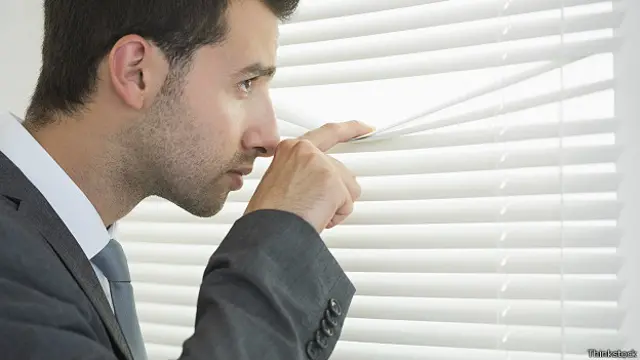 Мужчина подглядывает сквозь жалюзи
