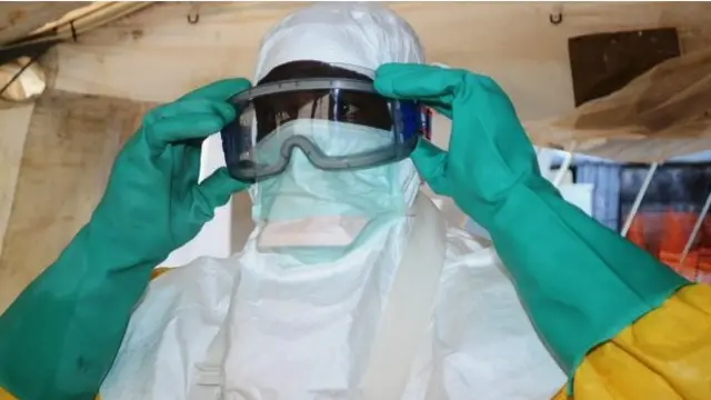 Một nhân viên y tế ở Conarky, Guinea, mặc đồ phòng vệ trước khi chăm sóc cho các bệnh nhân