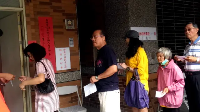 高雄某投票所外民眾排隊等候核對身份證（BBC中文網圖片29/11/2014）