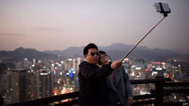 güney koreli bir çift özçekim çubuğuyla selfie çekiyor