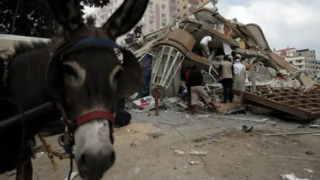 Палестинцы достают вещи из-под обломком дома